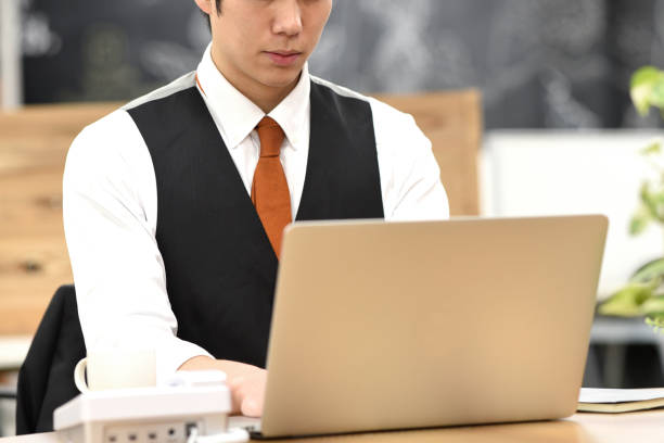 istock Asian young male office worker working on laptop indoors 1907509239