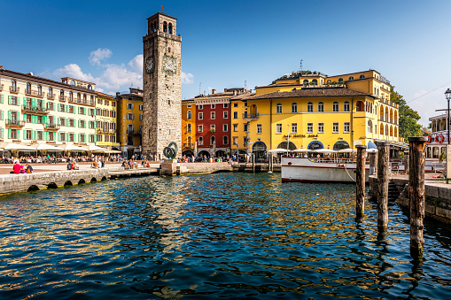 Riva del Garda, Italy - October, 04. 2023: Downtown Riva del Garda. Town square with restaurants and clock tower near harbor.