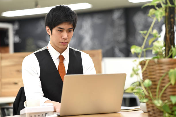 istock Asian young male office worker working on laptop indoors 1907516919
