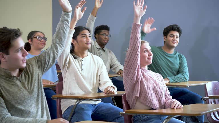 Multiracial high school students in class raising hands