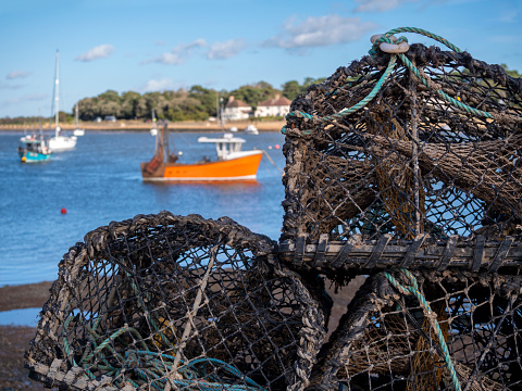 A pile of crab and lobster pots stacked on the riverbank of the River Deben at Felixstowe Ferry in Suffolk, Eastern England.