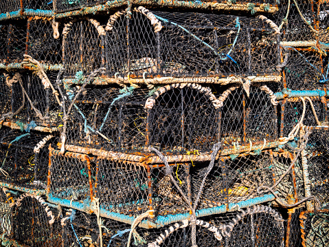 A pile of crab and lobster pots stacked on the riverbank of the River Deben at Felixstowe Ferry in Suffolk, Eastern England.