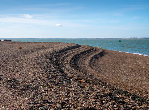 Ridges formed by the action of tide and waves in the pebbles on the beach at Landguard Point in Felixstowe, Suffolk, Eastern England. Across Harwich Harbour the distant coast of Essex can be seen.