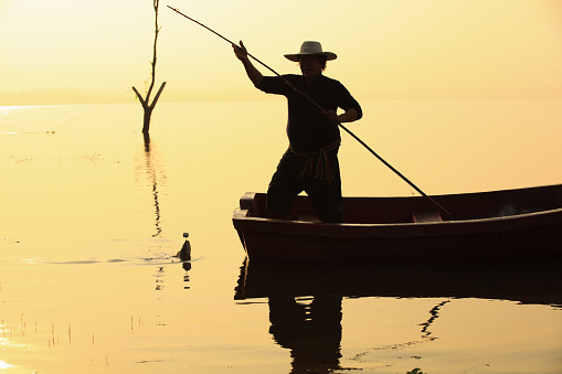 Man standing  and using rod and hook on boat to  fishing