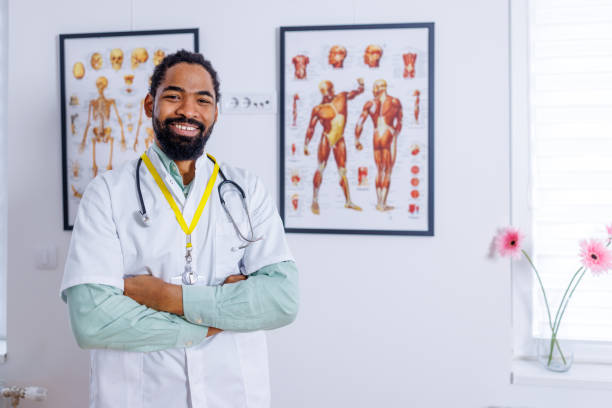 Happy pediatrician in medical clinic An image depicting a cheerful pediatrician, his happiness and care evident, as he stands ready in his medical clinic to tend to his young patients male nurse male healthcare and medicine technician stock pictures, royalty-free photos & images