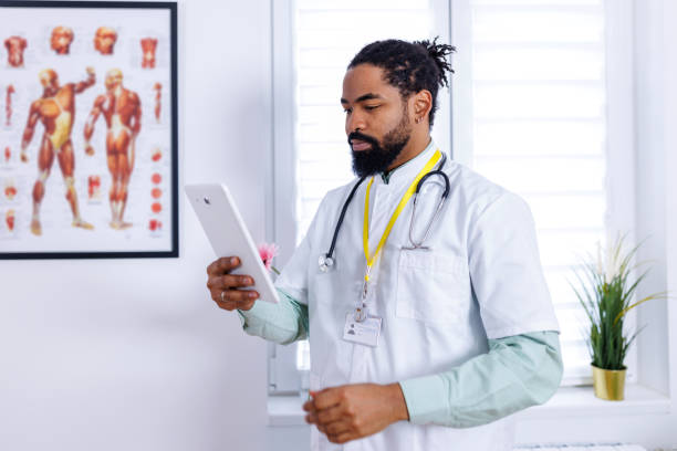 Medical professional's digital approach A captivating scene of a healthcare worker, a mid-adult man, utilizing wireless technology on a tablet, emphasizing the advancement of digital tools in medical practices male nurse male healthcare and medicine technician stock pictures, royalty-free photos & images
