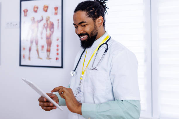 Surgeon's tech-savvy in hospital setting An inspiring image of a surgeon holding a tablet, his expression focused yet positive, signifying the crucial role of technology in surgical healthcare and patient management male nurse male healthcare and medicine technician stock pictures, royalty-free photos & images