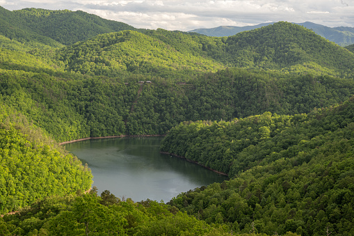 Fontana Lake in the Smoky Mountains - A serene landscape featuring the tranquil waters of Fontana Lake surrounded by majestic mountains, showcasing the harmonious beauty of nature's reflection and the peaceful serenity of the mountainous terrain.