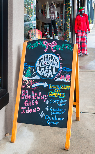 A holiday shop local sign on a sandwich board outside a clothing store in Brevard, North Carolina,