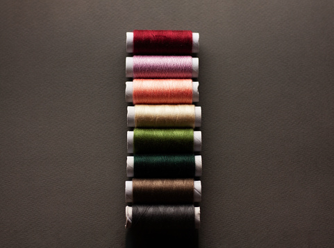 Colorful sewing threads on top of a gray cloth, top view