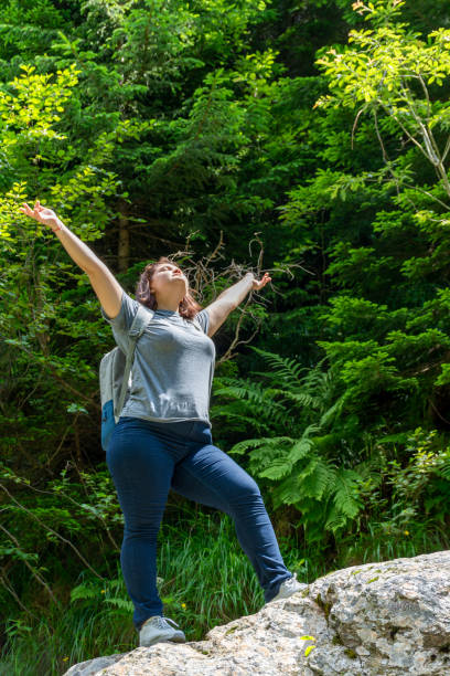 istock Female tourist with backpack standing on a rock in the forest 1907730997