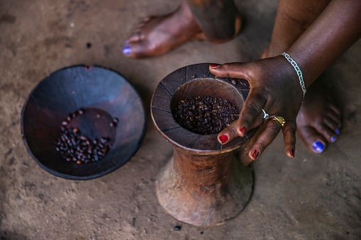 Ethiopian woman during coffee ceremony - grinding of beans in a wooden mortar and pestle, northern Ethiopia, Africa. A coffee ceremony is a ritualised form of preparing and later drinking coffee.