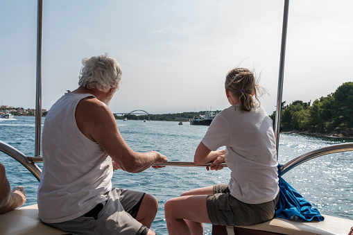 Two people on the boat, in background view on bridge Ždrelac connecting two island; Pašman and Ugljan. Sunny day, clear blue sky, some boats sailing under the bridge, Croatia
