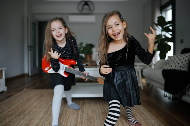 istock Cute girls playing guitar and singing 1907786251