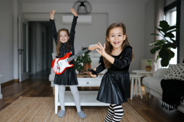 istock Cute girls playing guitar and singing 1907795878