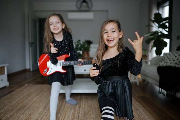 istock Cute girls playing guitar and singing 1907798306