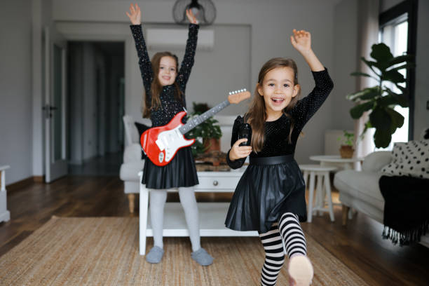 istock Cute girls playing guitar and singing 1907798452