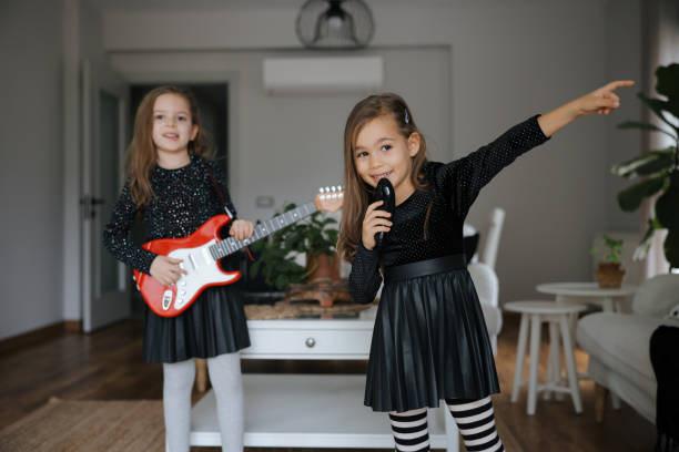 istock Cute girls playing guitar and singing 1907801554