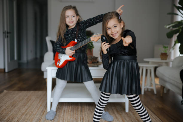 istock Cute girls playing guitar and singing 1907804168