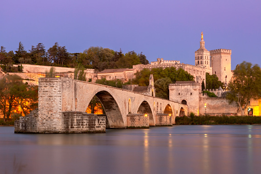 Famous medieval Saint Benezet bridge and Palace of the Popes during blue hour, Avignon, France