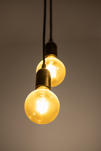 Glowing yellow light bulbs. Vintage fashionable edison lamps. Lighting, electricity, background with lamp. Light bulb on dark background