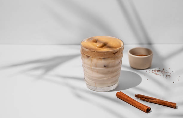istock Dalgona coffee. Whipped instant iced coffee with milk in a glass with cinnamon sticks on gray background with shadow. 1907839101