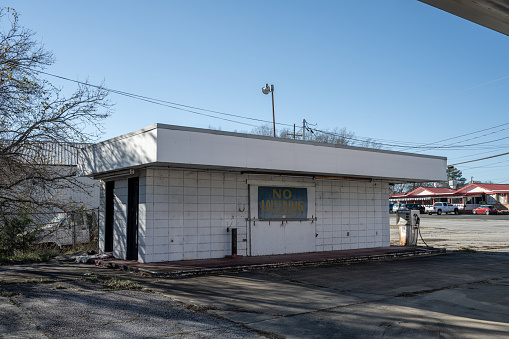 Lancaster, South Carolina, United States, 31 Dec 2023:   An  abandoned gas station in downtown Lancaster, South Carolina, marked by a no loitering sign.