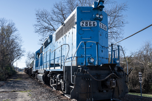 Lancaster, South Carolina, United States, 31 Dec 2023:   A  blue train traveling along tree-lined tracks in Lancaster, South Carolina.