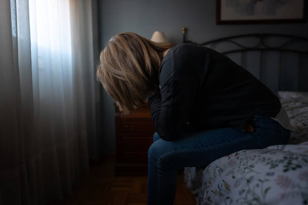 istock Woman sitting on bed with hands on face suffering from tiredness and depression 1907889805
