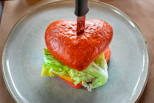 A heart-shaped burger on a plate is ready to eat. Custom menu for Valentine's Day