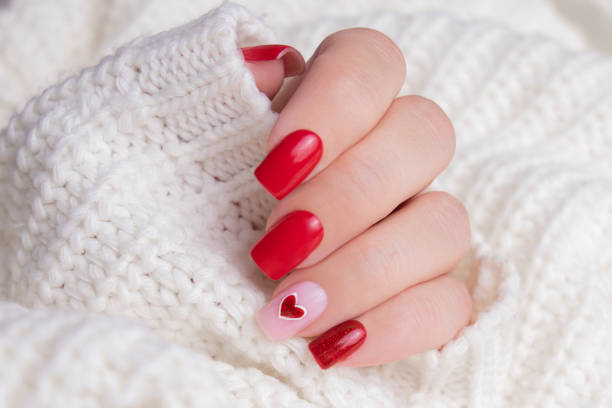 istock Female hand with red manicure nails, heart design 1907948164