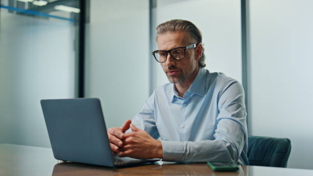 istock Serious boss video chatting laptop closeup. Confident man having web video call 1907954915