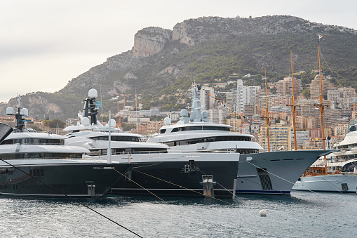 Few huge luxury yachts at the famous motorboat exhibition in the principality of Monaco, Monte Carlo, the most expensive boats for the richest people, mountain and residential complex on background. High quality photo