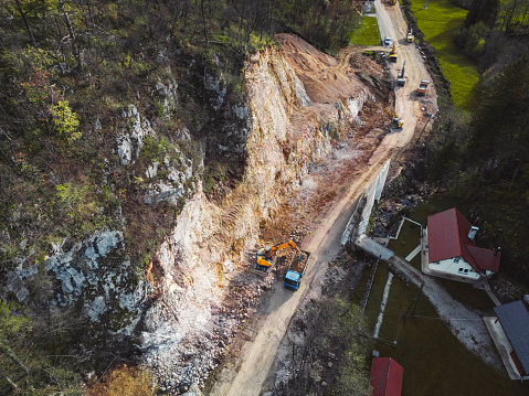 Aerial view of small quarry in the middle of beautiful green nature, top view shot of loaders and dump trucks working in quarry area