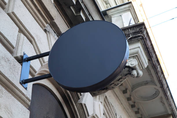 istock Blank billboard sign black round mockup in the urban environment on the facade, empty space to display your advertising or branding campaign. 1907985411