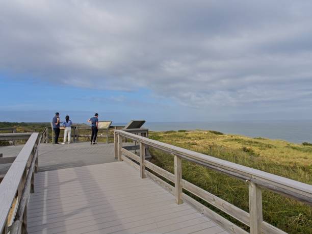 zwiedzający oglądają znaki informacyjne na plaży marconi, miejscu pierwszej transatlantyckiej transmisji radiowej między cape cod usa a anglią w wielkiej brytanii - sand dune audio zdjęcia i obrazy z banku zdjęć