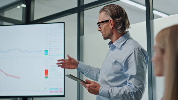 istock Confident man pointing screen in meeting room. Specialist presenting startup 1908020907