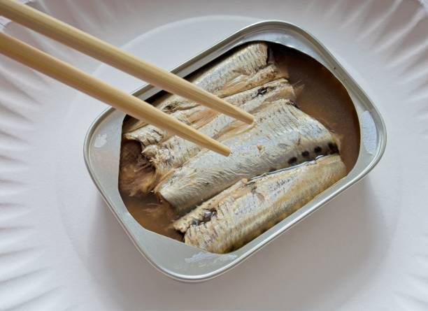 缶に入ったイワシと、魚を抜くのに箸が使われている