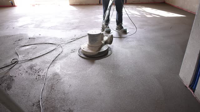 Construction worker, using power trovel to level concrete surface, at the construction site