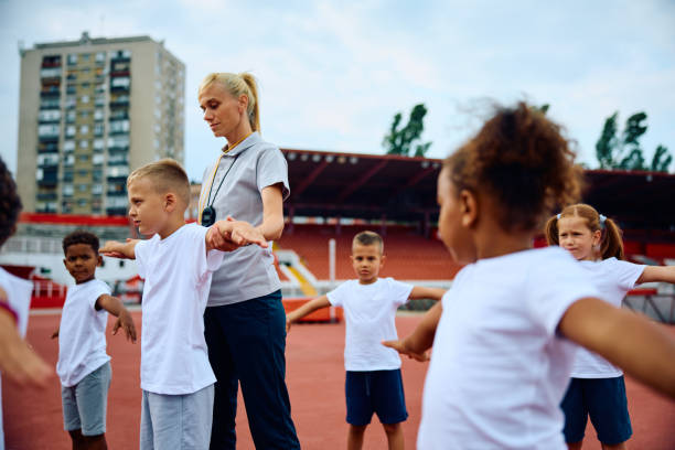 istock Group of children exercising during physical education class with their coach. 1908077784