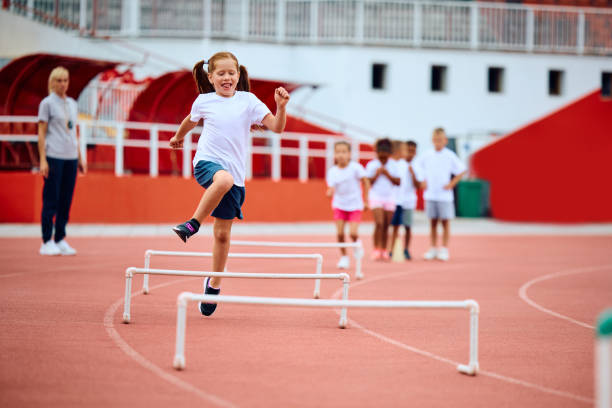 istock Happy girl jumping over obstacles while running at the stadium. 1908079347