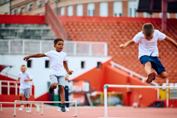 istock Little runners jumping over hurdles on running track at the stadium. 1908080059