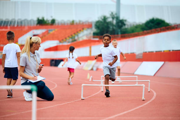 istock Black boy and his friends running on track with obstacles during exercise class at athletics club. 1908081429
