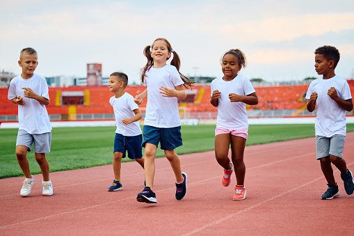Happy children running during sport training at the stadium. Copy space.