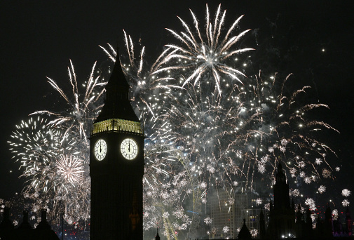 Iconic Big Ben surrounded by midnight fireworks at New Year, London UK