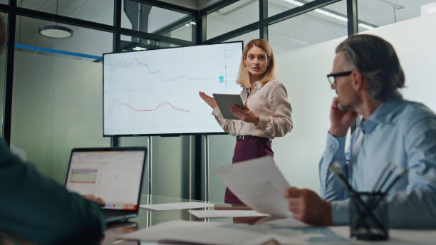 istock Business woman making presentation at modern tv office. Coach pointing at screen 1908173914