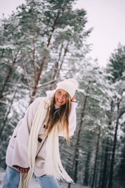 istock Active beautiful young woman in white clothes enjoying snowy winter forest 1908175457