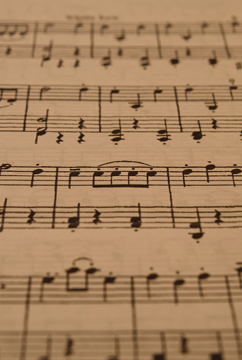 sheet music in the foreground with selective focus. with dotted eighth notes in front, tied