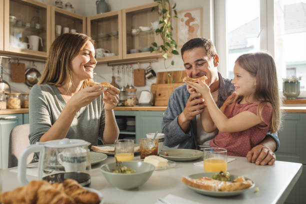 Family breakfast Young parents and their daughter talking while having breakfast. family get together stock pictures, royalty-free photos & images