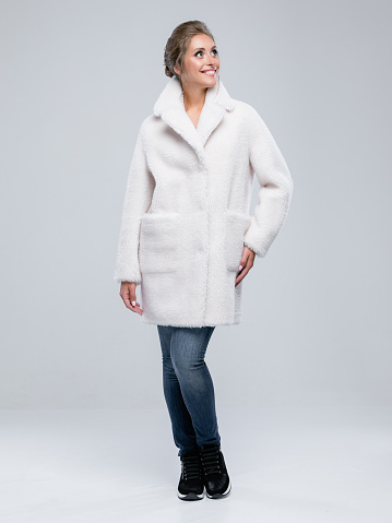 Female portrait in studio, woman wear winter coat. Grey background, concept photography of lookbook. professional model is posing for camera.